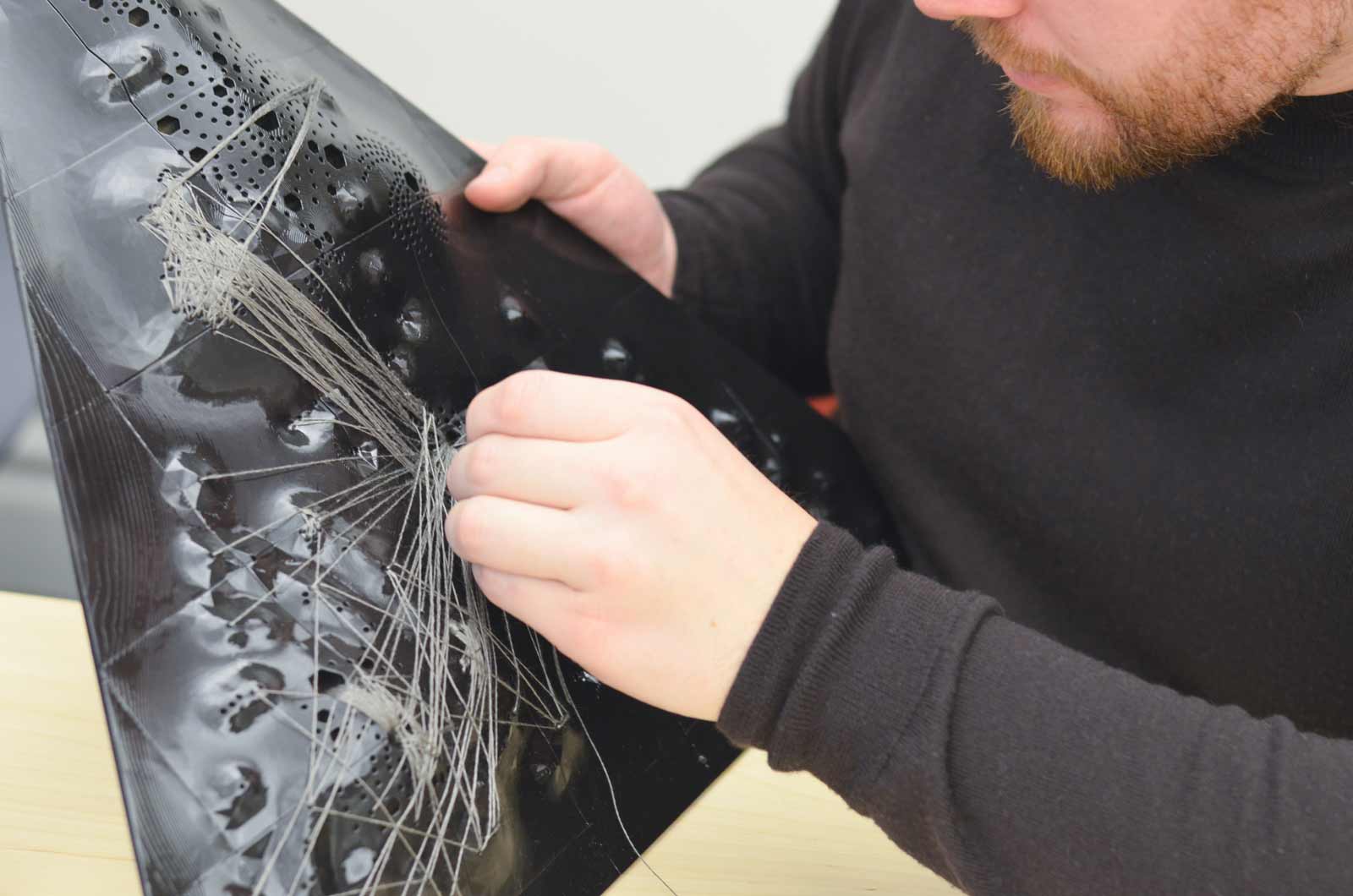 A man gathering eletrically conductive thread on the underside of the artwork.